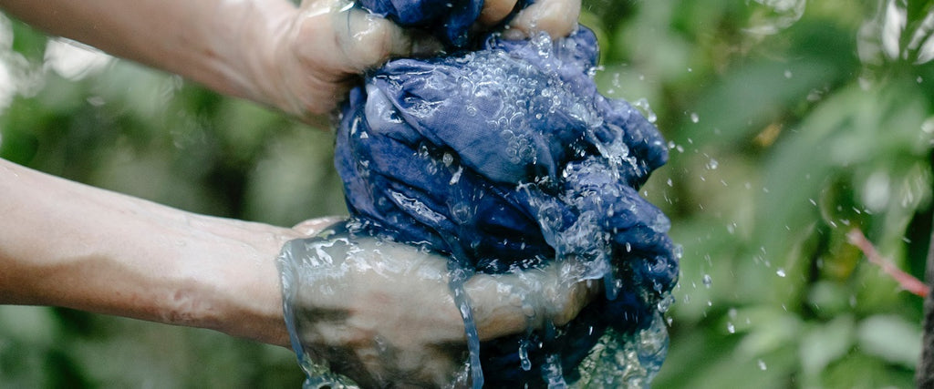 A person pressing out water of a dyed piece of cloth