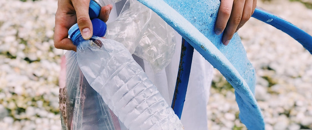 A hand picking up empty plastic bottles